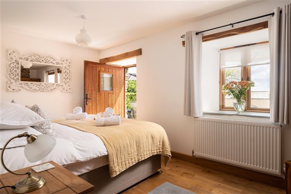 Corn Barn bedroom 3 arranged with a double bed with door open to terrace.